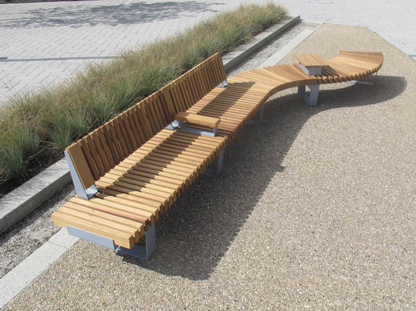 RailRoad Delta bench assembly comprising straight Start & Mid modules, curved Mid & End modules, with part-length backrest, armrest & tablet surface. Gallery Image