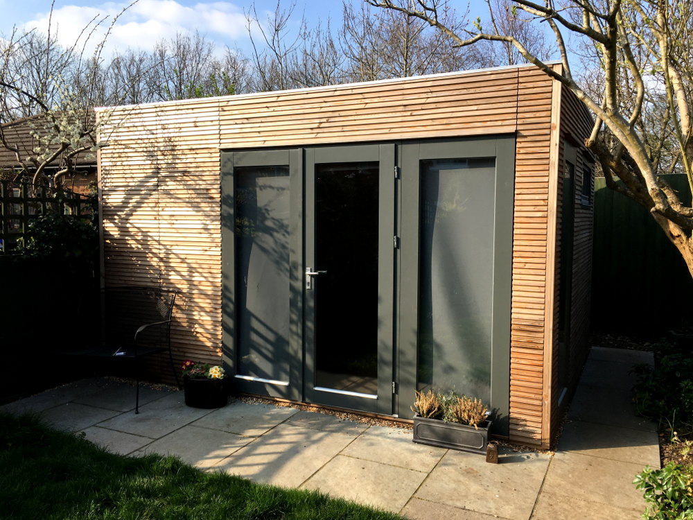Ultra modern garden office.  Horizontal profiled larch exterior walls.  No roof overhang, position close to a boundary.  Gallery Image