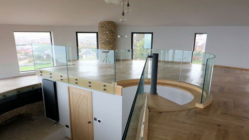 Channel set curved frameless glass balustrade above staircase and bolted glass balustrade to mezzanine floor edge Gallery Image